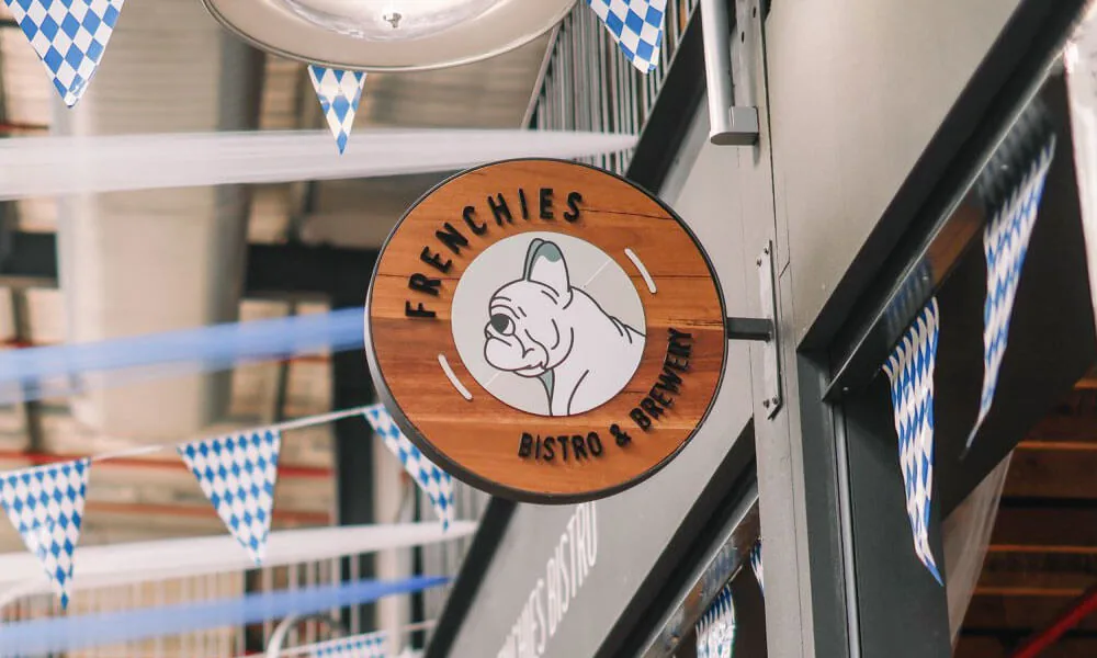 Enseigne ronde Frenchies Bistro & Brewery suspendue en salle